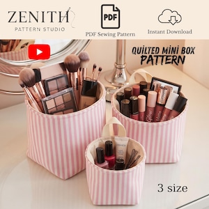 May include: Three cylindrical fabric storage boxes with a pink and white vertical striped pattern. The boxes are filled with various makeup brushes, palettes, lipsticks, and nail polish bottles. Text reads Zenith Pattern Studio and Quilted Mini Box Pattern.