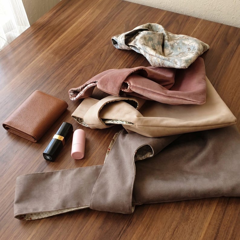 Peut inclure: Un ensemble de quatre sacs &agrave; nouer en tissu aux couleurs florales, vieux rose, beige et taupe, accompagn&eacute; d'un portefeuille en cuir marron, d'un tube de rouge &agrave; l&egrave;vres noir avec une bande dor&eacute;e et d'un petit r&eacute;cipient cylindrique rose.