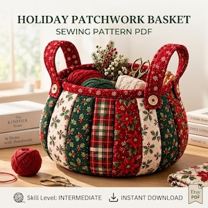 May include: A round fabric basket featuring a patchwork design of red and green holiday-themed patterns, including poinsettias, holly, and plaid. The basket has two red handles with wooden buttons and contains yarn, scissors, and greenery.