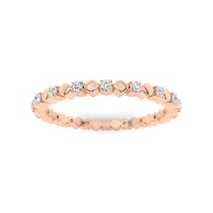 May include: Rose gold ring with a repeating pattern of diamond accents. The ring features a delicate design with small, round diamonds set within a geometric, openwork band. The ring is shown on a white background.