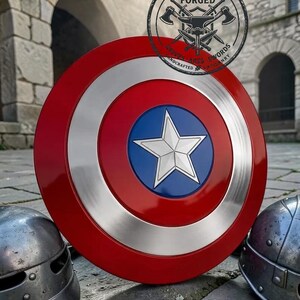 May include: A circular shield featuring a red outer ring, a silver metallic middle ring, and a blue center circle with a raised silver five-pointed star. A circular logo with the text VELORA FORGED KNIVES AXES SWORDS HANDCRAFTED ARTISANRY is visible.
