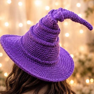 May include: A vibrant purple crochet hat featuring a wide, circular brim and a tall, pointed crown that curves downward at the tip. The hat is constructed from a dense, textured yarn stitch pattern, creating a structured and uniform appearance.