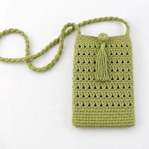 May include: A light green crochet phone bag with a long, braided strap. The bag features a decorative tassel and a geometric openwork design. The bag is approximately 7 inches tall and 4 inches wide.