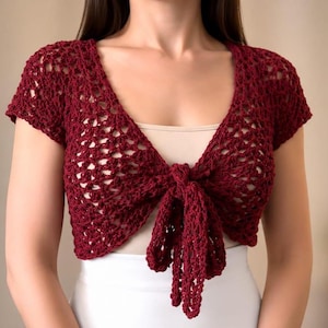 Peut inclure: Un boléro à manches courtes de couleur bordeaux profond, doté d'un motif en crochet ajouré, d'une encolure en V et d'un lien à nouer sur le devant. Le vêtement est réalisé en fil léger, présentant un design texturé et aéré au-dessus de la taille.