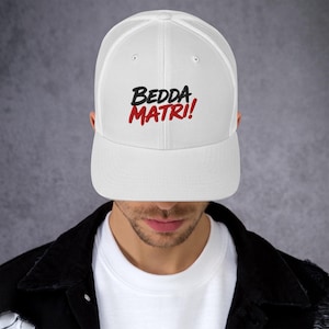 Può includere: Cappellino da camionista bianco con retro in rete e visiera curva. Il cappello presenta il testo ricamato "BEDDA MATRI!" in nero e rosso. Il cappello è indossato da una persona.