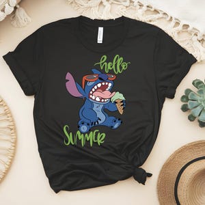 K&ouml;nnte beinhalten: Schwarzes T-Shirt mit einem Cartoon-Stitch-Design, das eine Sonnenbrille tr&auml;gt und Eis isst. Die Worte "hello summer" sind in gr&uuml;ner Schrift geschrieben. Das Design ist auf dem T-Shirt zentriert.