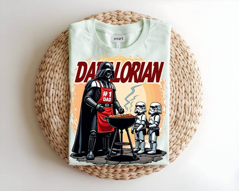 May include: A pale green t-shirt with a graphic of Darth Vader wearing a red apron that says "#1 Dad" grilling with two Stormtroopers. The shirt has the word "Darthlorian" in red text.