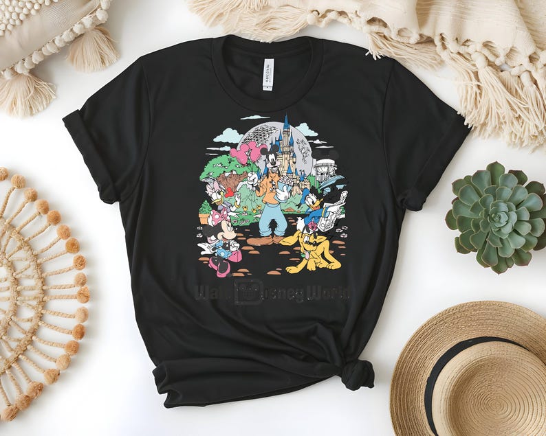 Puede incluir: Camiseta negra con un gr&aacute;fico colorido de personajes de Disney, incluyendo Mickey Mouse, Goofy y Donald Duck, frente a un castillo y el texto "Walt Disney World". El dise&ntilde;o est&aacute; impreso en una camiseta negra de cuello redondo.