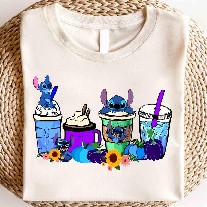 Puede incluir: Camiseta de color crema con un gr&aacute;fico colorido de personajes de Stitch con varias bebidas, calabazas y flores. El dise&ntilde;o incluye elementos azules, morados, verdes y amarillos, creando una est&eacute;tica l&uacute;dica y caprichosa.