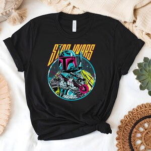 May include: Black t-shirt with a graphic of a Star Wars character in a circle. The character is wearing a helmet and holding a weapon. The words "STAR WARS" are printed above the character in yellow and orange.