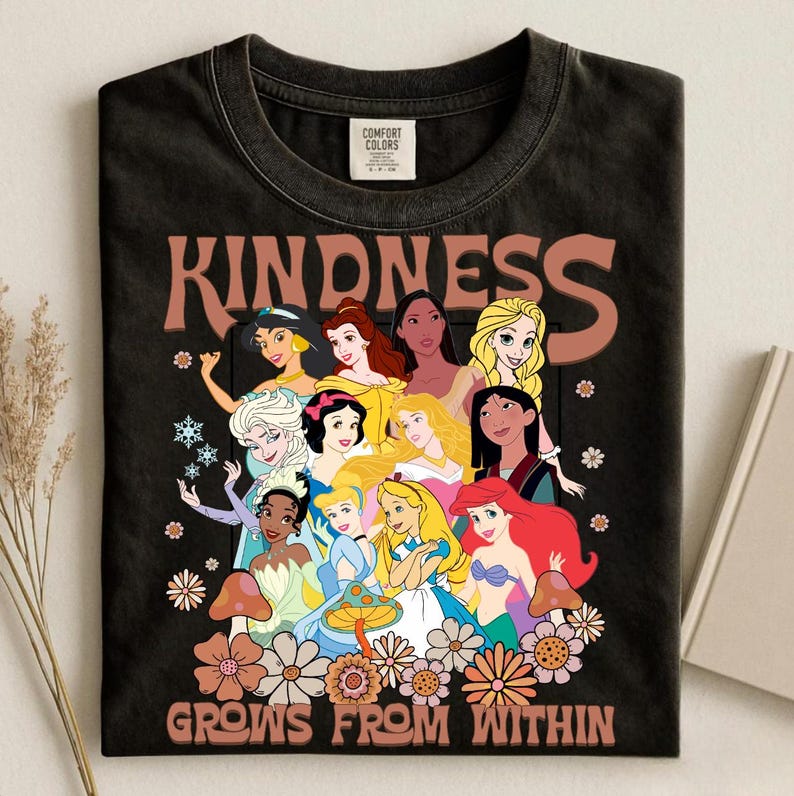 May include: Black t-shirt featuring a graphic of various cartoon princesses with the word "KINDNESS" above them. The phrase "GROWS FROM WITHIN" is printed below the princesses, with floral and mushroom accents.