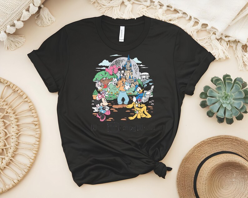 Puede incluir: Camiseta negra con un gr&aacute;fico colorido de personajes de Disney, incluyendo Mickey y Minnie Mouse, Goofy, Donald Duck y Pluto, frente a un castillo y una gran esfera. El texto "40 Years of Memories" est&aacute; en la parte inferior.