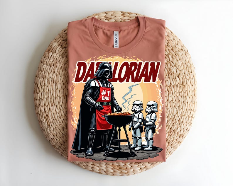 May include: A terracotta t-shirt with a graphic of Darth Vader at a barbecue. The design includes the text "DADORIAN" and "#1 DAD", plus Stormtroopers. The image is set against a sunset-like background.