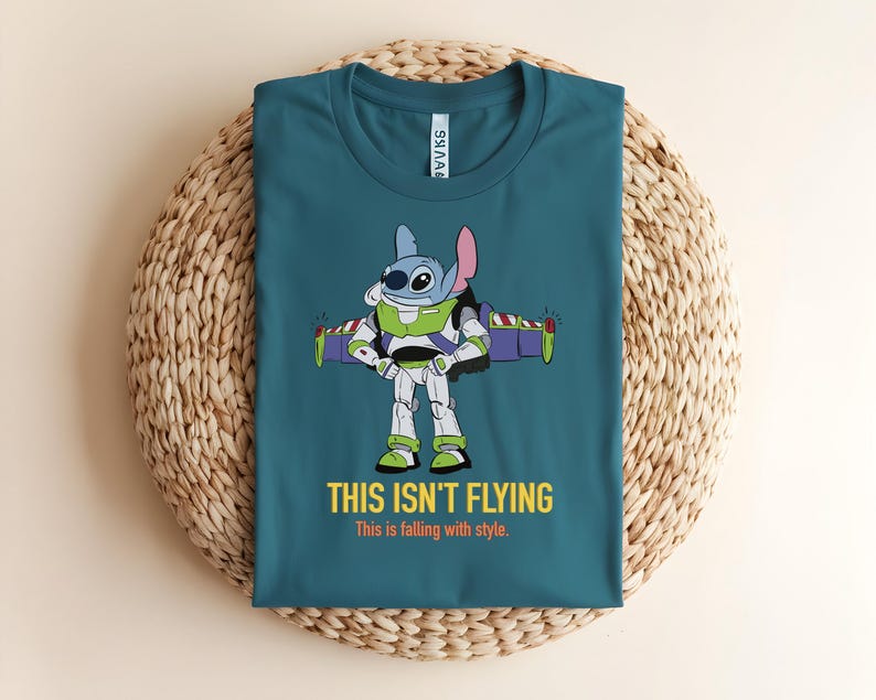 May include: Teal t-shirt featuring a cartoon character fusion of Stitch and Buzz Lightyear. The graphic shows Stitch in Buzz's spacesuit with the text "THIS ISN'T FLYING" and "This is falling with style."