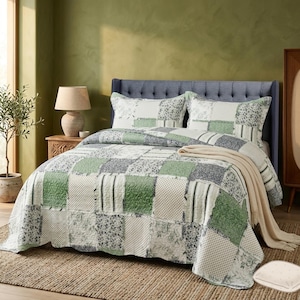 May include: A patchwork quilt set in green, white, and grey squares. The quilt features floral and dotted patterns, with a matching pillow and a beige throw blanket. The headboard is blue with a checkered design. The bed is on a woven rug.