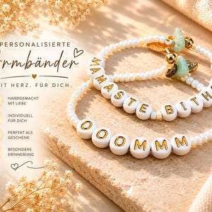 Könnte beinhalten: Zwei weiße Perlenarmbänder mit goldenen Buchstaben, die "MAMASTE BITCHES" und "OOOMMM" buchstabieren. Die Armbänder haben goldene Akzente und Charms. Der Hintergrund ist hellbraun mit floralen Akzenten.