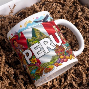 Puede incluir: Una taza de cerámica blanca con un diseño gráfico colorido que muestra la bandera peruana, Machu Picchu, una llama, un cóndor, un colibrí y comida tradicional. La palabra PERU está impresa en letras mayúsculas blancas grandes en el centro.