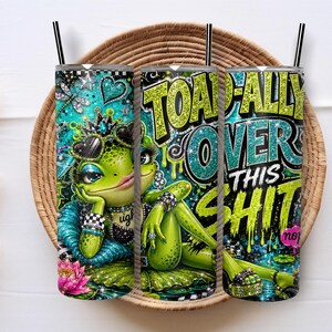Puede incluir: Un vaso cilíndrico de acero inoxidable con pajita negra, que presenta un gráfico de una rana verde con corona, gafas de sol en forma de corazón y joyas. El texto TOAD-ALLY OVER THIS SHIT aparece en letras brillantes de color verde lima y turquesa.