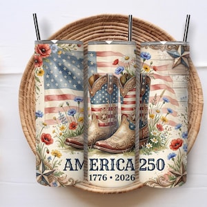 May include: Three cylindrical tumblers with black straws featuring a patriotic design of cowboy boots, American flags, wildflowers, and stars. The text AMERICA 250 and 1776-2026 is printed in blue at the base of the tumblers against a cream background.