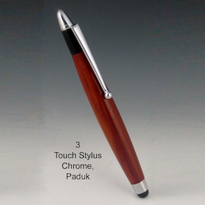 May include: A touch stylus pen with a chrome clip and tip, and a Paduk wood barrel. The pen has a black tip for use on touch screens. The text "3 Touch Stylus Chrome, Paduk" is visible on the image.
