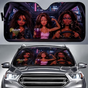 May include: Car windshield sunshade featuring a humorous image of three dolls in a car. One doll holds a margarita, another flexes, and the third drives. The background shows a city at night.