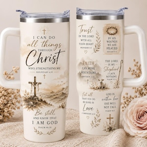 May include: Two cream-colored stainless steel tumblers with handles and clear lids. The tumblers feature brown printed religious text and illustrations, including a cross, a crown of thorns, mountains, a lamb, and various Bible verses.