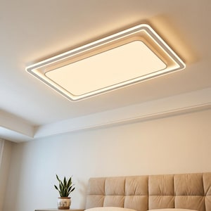 Puede incluir: Una moderna lámpara de techo rectangular con marco blanco y luz cálida. La lámpara está empotrada en el techo y tiene un diseño en capas. La imagen muestra la lámpara en un dormitorio.