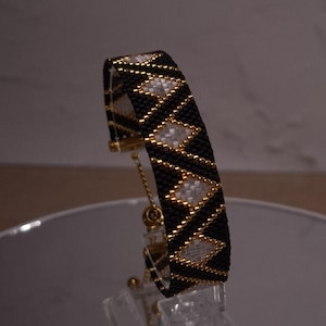Handmade beadwoven bracelet featuring repeating diamond shapes.