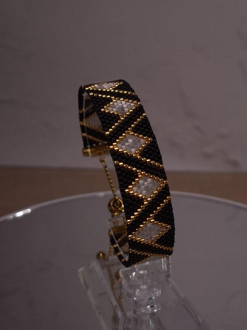 Handmade beadwoven bracelet featuring repeating diamond shapes.