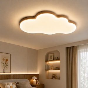 May include: A cloud-shaped ceiling light fixture with a warm, diffused glow. The light has a wooden frame and is mounted on a white ceiling. The fixture is a soft, inviting design element for a bedroom or nursery.