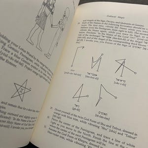 May include: Open book with illustrations and text about Zodiacal Magic. The pages show drawings of figures, symbols, and Hebrew text. Instructions are provided for rituals, including vibrating names and tracing sigils.