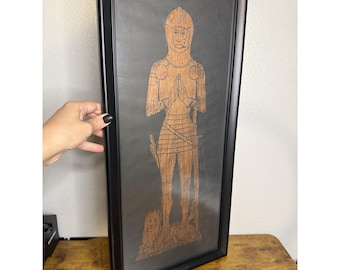 Retrato medieval emoldurado, impressão em latão com decalque dourado sobre fundo preto.