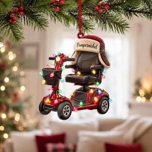 May include: A red mobility scooter Christmas ornament decorated with colourful string lights. A brown and cream-coloured trapper hat with the name Pumpernickel printed on the front rests on the seat. The ornament hangs from a red ribbon.