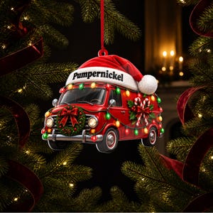 May include: A red van Christmas ornament featuring a Santa hat on the roof with the text Pumpernickel, decorated with a green wreath, candy canes, and colourful string lights, hanging from a red ribbon against a dark evergreen tree background.
