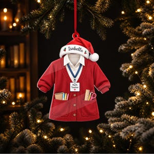 Peut inclure: Une décoration en forme de gilet rouge avec un col de chemise blanc, un cordon bleu avec un badge blanc marqué Math Teacher, et un bonnet de Père Noël rouge avec le nom Isabella imprimé. Les poches contiennent un carnet, des stylos, une règle et des ciseaux.