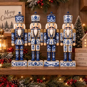 Peut inclure: Quatre figurines de casse-noisettes debout arborant un motif floral bleu et blanc rappelant la porcelaine. Chaque figurine porte un grand chapeau et un uniforme avec des détails dorés, sur un socle rectangulaire orné de motifs botaniques.