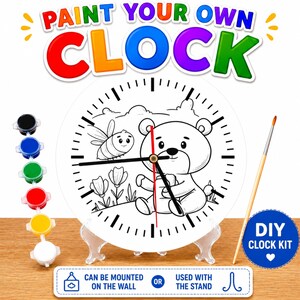 May include: A DIY clock kit with a white clock face featuring a bear and bee design. The kit includes paint pots in various colors and a paintbrush. The clock can be mounted on the wall or used with the stand. The text "PAINT YOUR OWN CLOCK" is at the top.