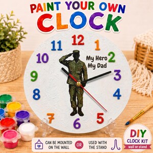 Może przedstawiać: Zestaw zegara DIY z białą tarczą, kolorowymi cyframi i figurką salutującego żołnierza. Zegar pokazuje "My Hero My Dad". Zawiera pojemniki z farbą i stojak. Tekst "Paint Your Own Clock" znajduje się na górze.