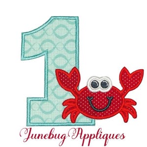 May include: A turquoise blue number one with a red crab with white eyes and a red smile. The crab is in front of the number one. The text "Junebug Appliques" is at the bottom of the image.