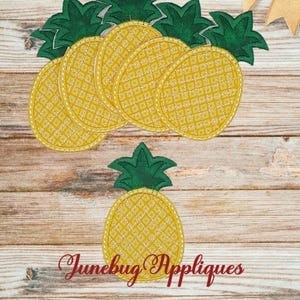 May include: Six yellow pineapple-shaped fabric appliques with green leaves. The appliques are arranged in a circle with one pineapple in the center.