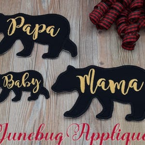 May include: Three black felt bear appliques with gold embroidery. The bears are in different sizes and each has a different word embroidered on it: "Papa", "Mama", and "Baby".