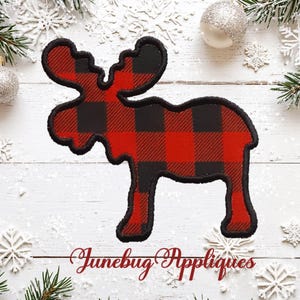 May include: A moose-shaped fabric applique featuring a red and black buffalo plaid pattern with a thick black stitched border. The text Junebug Appliques is written in a red cursive script below the moose shape on a white wooden surface.