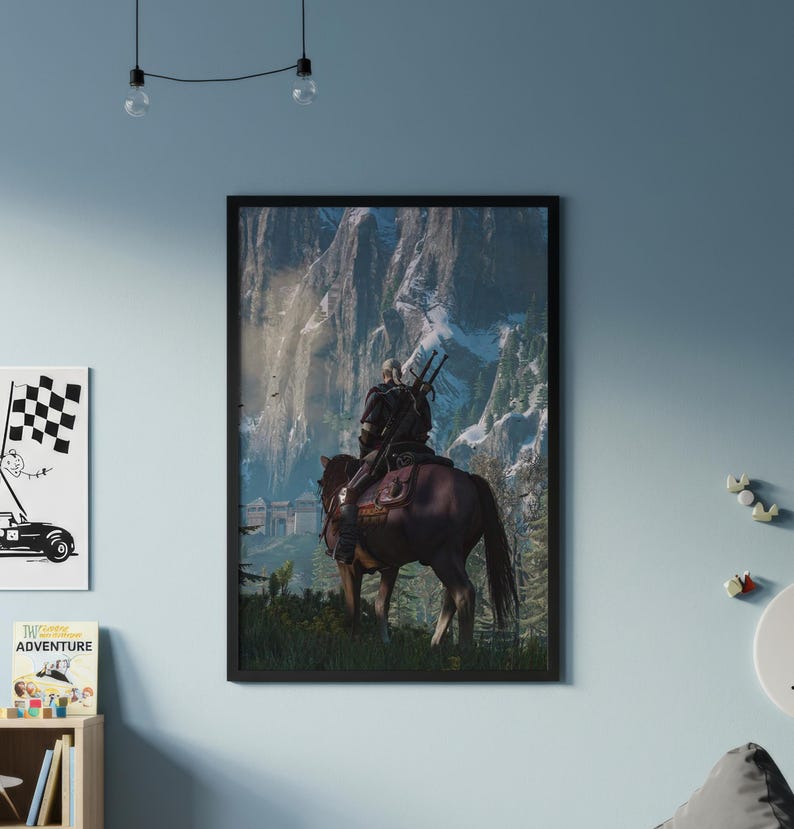 May include: A framed vertical wall art print depicting a figure with long white hair riding a brown horse, viewed from behind. The rider carries two swords on their back, facing tall, snow-capped mountain peaks and a stone fortress structure.