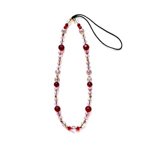 May include: A beaded lanyard with clear and red beads and gold-coloured spacers. The lanyard has a black cord loop for attaching to a phone or other small device. The beads are various shapes and sizes.