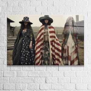 May include: Three figures stand in a rural setting wearing long dresses and capes. The left figure wears a star-patterned dress and hat. The centre figure wears a red and white striped cape over a patterned dress. The right figure wears a hooded cape.