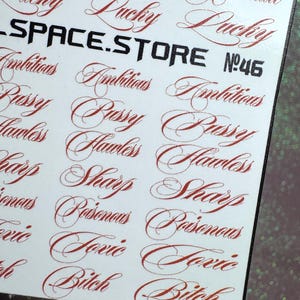 Op de afbeelding: Een vel stickers met diverse woorden in een rood, elegant script. Woorden zijn onder meer "Lucky", "Ambitious", "Pussy", "Flawless", "Sharp", "Poisonous", "Toxic" en "Bitch". De tekst "SPACE.STORE" staat in vette, zwarte letters.