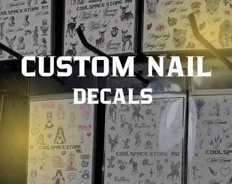 May include: Multiple sheets of nail decals in clear plastic packaging, each featuring various graphic designs including animals, figures, and text. The sheets are labeled with COOLSPACE.STORE and specific numbers, displayed on a retail pegboard.