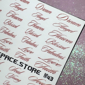 Może przedstawiać: Arkusz białych naklejek z czerwonymi słowami pisanymi kursywą, takimi jak "Dream", "Angel" i "Heaven". Tekst "SPACE.STORE" jest pogrubioną czarną czcionką, z "№43" poniżej. Naklejki są na białym tle.