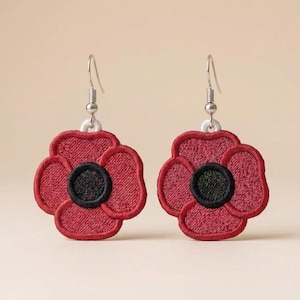 May include: A pair of red poppy flower earrings with black and green centres. The earrings are embroidered with a detailed design and have silver-coloured fish hook ear wires. The poppy flowers are a vibrant red colour.