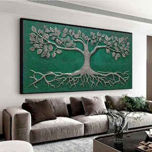 Peut inclure: Une grande œuvre d'art murale rectangulaire avec un motif d'arbre argenté sur un fond vert émeraude texturé. L'arbre présente des feuilles, des branches et des racines détaillées, encadrées d'un bord noir. L'œuvre est affichée au-dessus d'un canapé gris.